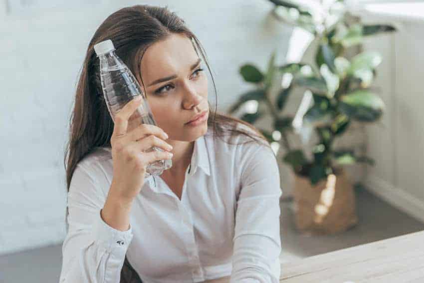 Uncomfortable-Hot-Business-Woman-Trying-to-Cool-Off-With-Cold-Water-Bottle