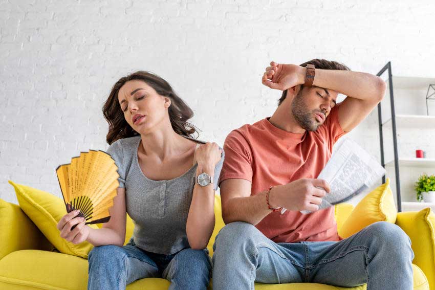 Uncomfortable-Hot-Couple-Sitting-on-Couch-Faning-the-Heat - No Unit