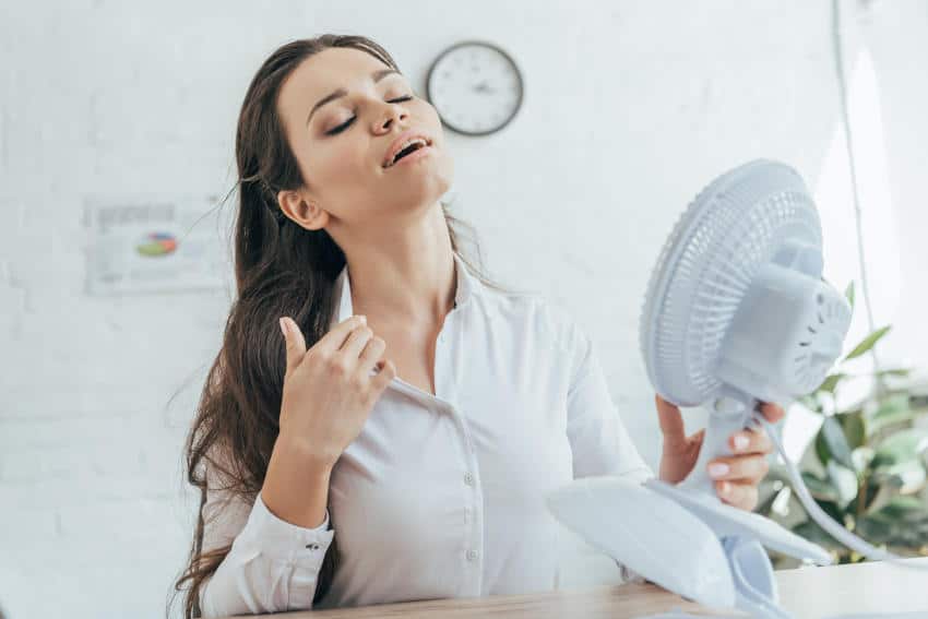 Uncomfortable-Hot-business-woman-cooling-off-with-Fan